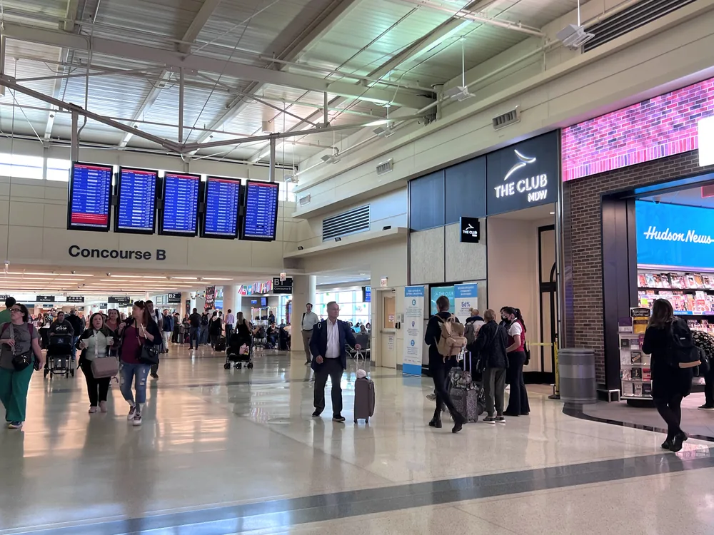 Concourse B departure boards and travelers at Midway International Airport