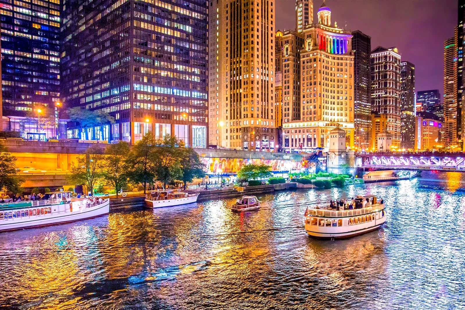 Chicago Riverwalk lit at night with tour boats