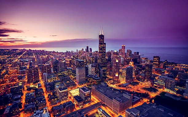 Chicago skyline under a purple and orange sunset from the air